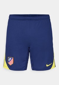 Marineblå sportshorts med gule detaljer, der har et teamlogo-patch og et lille Nike-swoosh. Lavet af åndbart stof.
