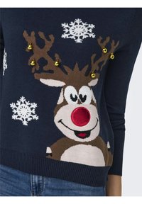 Pull-over bleu marine avec un motif de renne affichant un nez rouge, des bois bruns, des flocons de neige blancs et des grelots dorés brillants. Texture en maille douce.