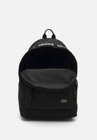 Black backpack made of durable fabric, featuring a rounded flap, mesh interior, and distinct green crocodile logo on the front.