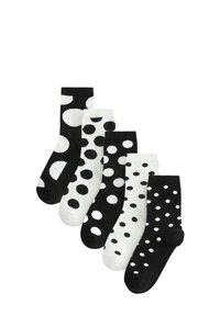 Trzy pary skarpetek w czerni i bieli z różnymi wzorami w kropki. Materia�ły są miękkie i elastyczne, zaprojektowane z myślą o komforcie.