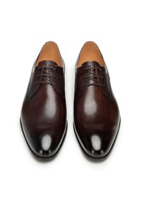 Chaussures en cuir marron avec une finition lisse et un accent texturé sur les côtés, dotées d'un bout pointu et d'un design traditionnel à lacets.