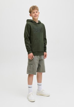 Sudadera con capucha verde oscuro con bolsillo frontal tipo canguro y logo; pantalones cortos cargo grises claros con bolsillos laterales; zapatillas blancas y calcetines tobilleros.