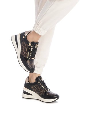 Baskets montantes noires et imprimé léopard avec des accents dorés, dotées d'une fermeture éclair et d'une semelle blanche épaisse. Cuir texturé et matériaux lisses.