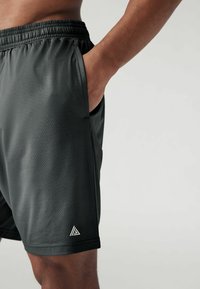Sorte sportsbukser med en tekstureret, honningkcomb-mønster. Har elastisk talje og sidelomme, med en lille hvid logo-accent.