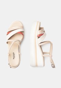 Beige platform sandals with cross straps in light beige, white, and coral accents. Smooth leather finish with adjustable ankle strap.