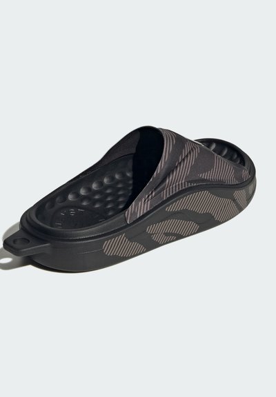 Black slip-on sandal featuring a textured sole with a cushioned interior, striped fabric upper, and a distinctive patterned design.