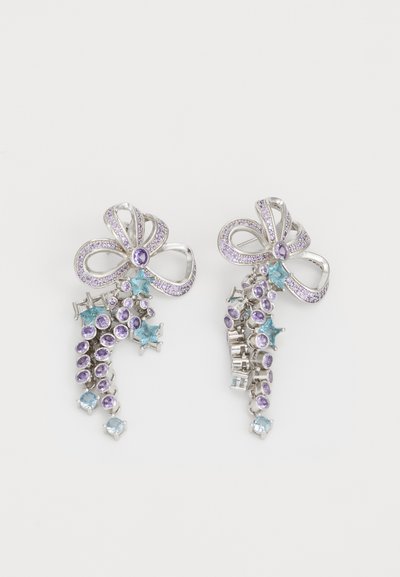 Boucles d'oreilles en argent en forme de nœuds avec des pierres violettes et bleues, présentant des designs élaborés et des formes variées, y compris ronde et étoilée.