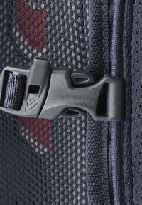 Marineblauer Mesh-Stoff mit texturierter Oberfläche, ausgestattet mit einer schwarzen Kunststoffschnalle und Nylongurten, zeigt einen teilweise roten Hintergrund hinter dem Mesh.