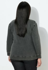 Sudadera de manga larga en gris carbón con un ajuste holgado, costuras oversize y puños acanalados. Cuenta con un escote redondo y una textura suave.