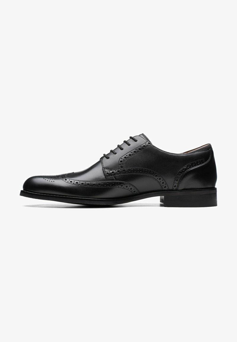 Mustad mustris kingad mustast nahast, brogue detailide ja sileda tekstuuriga, ümmarguse varbaga, lame konts ja klassikaline nöörimise disain.