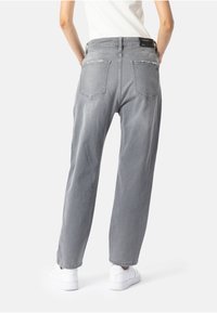 Sive visoke traperice s opuštenim fitom i pet džepova. Imaju uočljivo izbljeđivanje i mekanu teksturu denima.