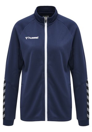Marineblauwe zip-up trainingsjack met textuurvezel, witte rits en contrasterende zwart-witte chevronstrepen op de mouwen. Hummel-logo op de borst.