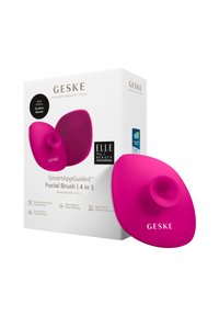 Spazzola per il viso in silicone rosa brillante con un supporto centrale a suzione, superficie testurizzata e forma ergonomica. La scatola presenta i dettagli del prodotto e il branding.