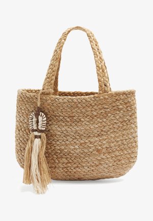 Gevlochten shopper van natuurlijke vezels met twee gevlochten handvatten en een decoratieve kwast van bijpassende vezels die aan één handvat hangt.