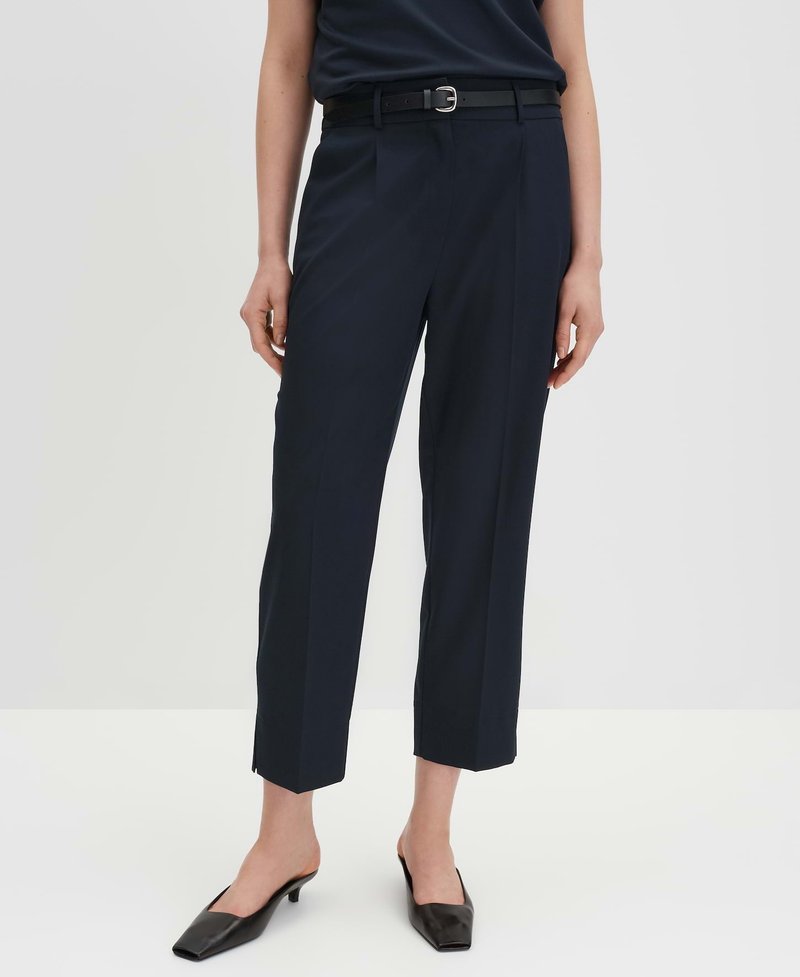 Marineblaue, maßgeschneiderte Hose mit geradem Schnitt, gefälteltem Vorderteil und knöchellanger Länge. Sie verfügt über einen schwarzen Gürtel mit einer silbernen Schnalle und schrägen Taschen.