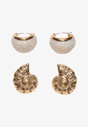 Deux paires de boucles d'oreilles : créoles en croissant crème et or, et coquillages spirales dorés incrustés de strass clairs.