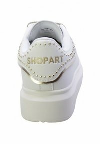 Sneaker bianco con tomaia in pelle liscia, dettagli con borchie sul tallone e testo dorato "SHOPART". Presenta una suola spessa bianca.