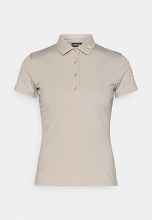 Beige pikétröja i mjukt tyg, med klassisk krage, knäppning framtill, korta ärmar och en liten logotyp på kragen.