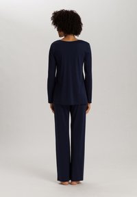 Ensemble de pyjama bleu marine en tissu doux ; haut à manches longues avec un col arrondi et un pantalon ample. Texture lisse, design minimaliste.