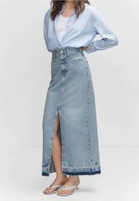 Vaaleansininen farkku-maxihame, jossa on edessä halkio, risat helmat ja korkea vyötärö. Yhdistettynä vaaleansinisellä paidalla ja hopeisilla sandaaleilla.