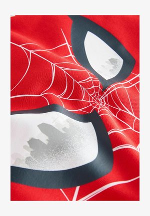 Punainen kangas, jossa on Spider-Man-kuvio, jossa on suuret valkoiset ja mustat silmämuodot, päällystettynä valkoisilla hämähäkkiverkkomalleilla.