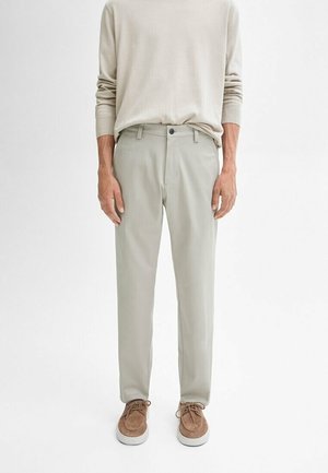 Jasnoszare spodnie z miękkiego materiału, o prostym kroju, z zapięciem na guzik i kieszeniami bocznymi, w połączeniu z jasnobeżową koszulą z długim rękawem.