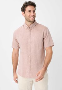 Camicia a maniche corte, con bottoni, di colore rosa chiaro, realizzata in tessuto testurizzato, con taschino sul petto e bottoni a contrasto.