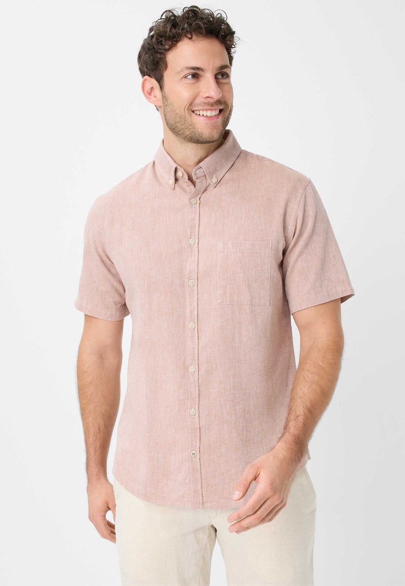 Camicia a maniche corte, con bottoni, di colore rosa chiaro, realizzata in tessuto testurizzato, con taschino sul petto e bottoni a contrasto.