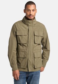Chaqueta verde oliva con cuello alto y varios bolsillos frontales grandes. Fabricada con un tejido liviano y un acabado texturizado.