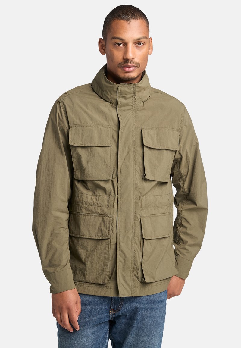 Chaqueta verde oliva con cuello alto y varios bolsillos frontales grandes. Fabricada con un tejido liviano y un acabado texturizado.
