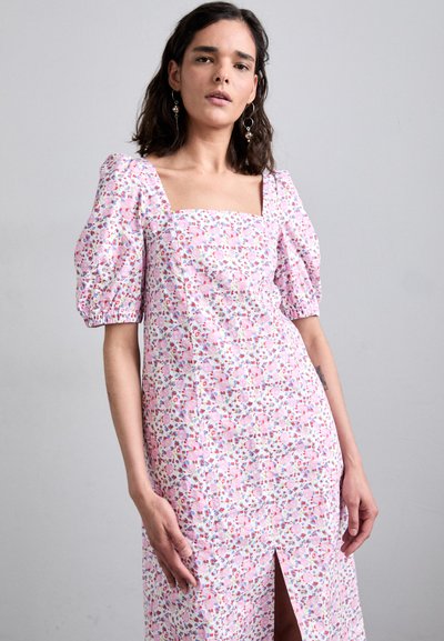 Cvečni natis obleka v nežno roza barvi z napihnjenimi rokavi in kvadratnim izrezom. Značilna je sprednja razporka za dodatno oblikovanje.