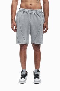 Grå bomullsshorts med elastisk midje, med sidesømmer, avslappet passform og kontrasterende sømmer. Brukt med hvite joggesko.