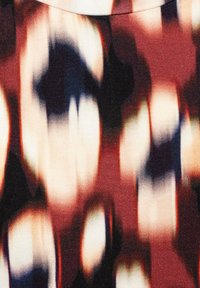 Abstracte gebloemde stof in rode, zwarte en witte tinten. De textuur is soepel met een zachte, gemengde uitstraling, met vage vormen.