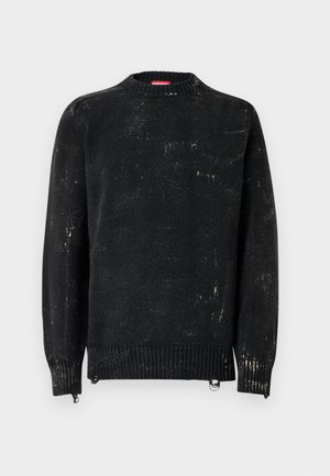 Melns adīts džemperis ar apaļu apkakli, ribotām aprocēm un apakšu. Raksturots ar nodiluma tekstūru un gaišākiem marķējumiem. Sānos rāvējslēdzēji regulēšanai.