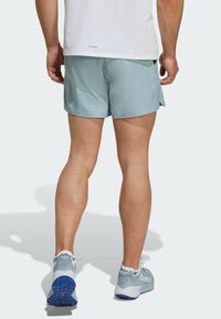 Bermudas deportivas de color azul claro con una textura suave, que cuentan con un corte holgado y aberturas laterales. Combinadas con zapatillas TERREX de color azul claro con suelas de color azul oscuro.