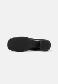 Black shoe sole with a textured, rubber surface. Features a curved shape and a slightly raised heel with minimal tread pattern.
