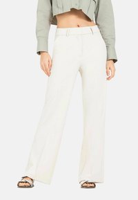 White wide-leg trousers with a sleek design, featuring a flat front, belt loops, and a smooth texture. Paired with a cropped gray shirt.
