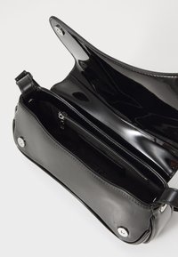 Borsa a tracolla nera in pelle verniciata con una finitura lucida, dotata di una tasca interna con zip, chiusura a scatto e tracolla staccabile. Design strutturato.