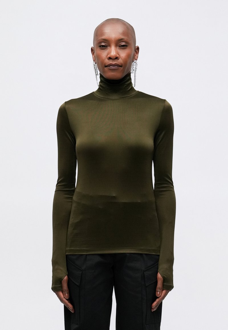 Top verde măsliniu cu guler înalt, confecționat dintr-un material neted și elastic; are mâneci lungi cu orificii pentru degete și un design sleek, ajustat.
