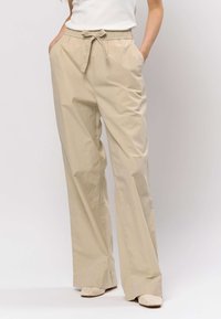 Beiget, kevyet, leveälahkeiset housut, joissa on joustava vyötärönauha ja solmimisnauhat, sivutaskut ja sileä pinta.