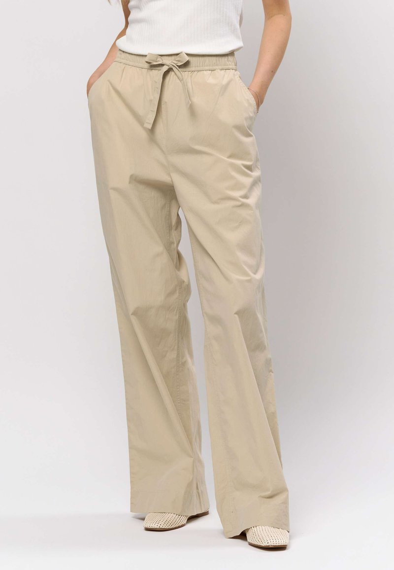 Beiget, kevyet, leveälahkeiset housut, joissa on joustava vyötärönauha ja solmimisnauhat, sivutaskut ja sileä pinta.