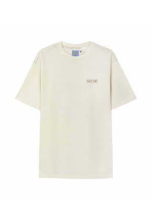 Bawełniany t-shirt w kremowym kolorze, z krótkimi rękawami, okrągłym dekoltem oraz małym brązowym logo „SRF.INC” na piersi. Miękka tekstura.