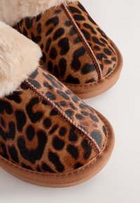 Papučky s leopardím vzorom, s umelým kožúškom vo vnútri, zaoblenou špičkou a hnedou gumovou podrážkou. Má kontrastné prešívanie pozdĺž švov.