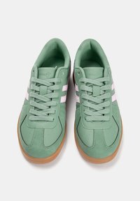 Baskets vertes en cuir souple, avec des rayures roses, bout arrondi, surface texturée, et semelle en caoutchouc naturel. Fermeture à lacets.