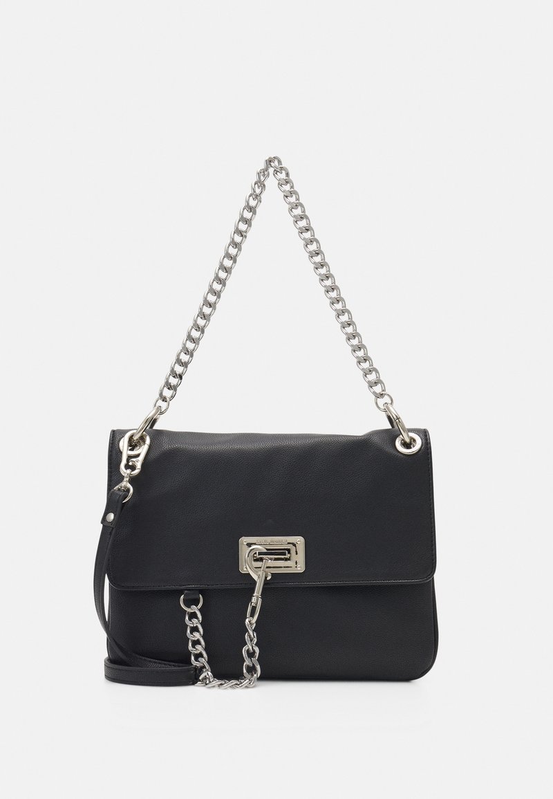 Sac à bandoulière en cuir noir avec une bandoulière en chaîne argentée, une fermeture rectangulaire argentée et un détail en cuir amovible sur un fond uni.