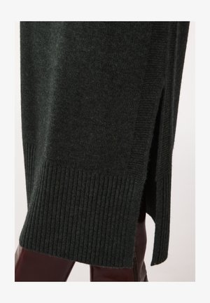 Dunkelgrüner gestrickter Pullover mit geripptem Saum und seitlichen Schlitzen, der eine weiche Textur und eine figurbetonte Silhouette präsentiert.