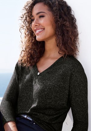 Schwarzes, strukturiertesLangarmshirt mit V-Ausschnitt und einem dekorativen Knopf am Kragen. Getragen mit dunklen Hosen vor einem hellen Hintergrund.