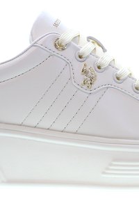 Vit sneaker med övre del i syntetiskt läder, texturerade sidor, guldlogga och snörning med platta, vita skosnören.