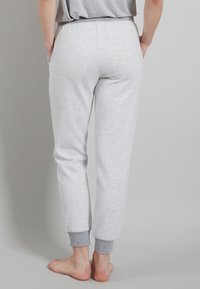 Pantaloni sportivi grigi con una texture morbida, design a gamba affusolata e caviglie con polsino. Presenta tasche laterali e una vita elastica.
