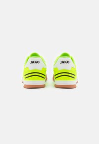 Neon žalia sportinė avalynė su balta kulnu, juodais akcentais ir guminėmis padais. Prekės ženklas "JAKO" nurodytas ant nugaros.